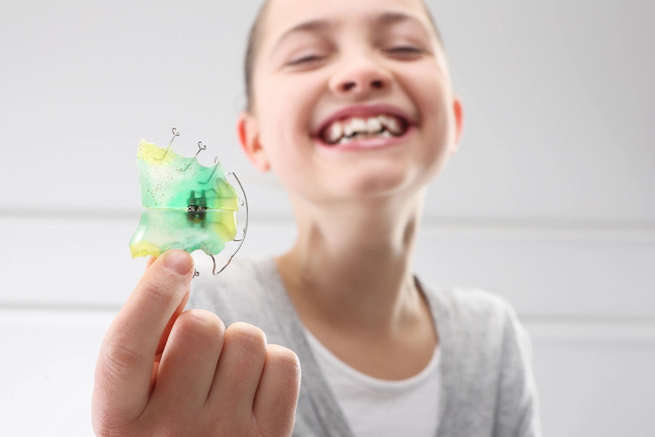 A child holding an orthodontic Hawley retainer made by an orthodontic lab.